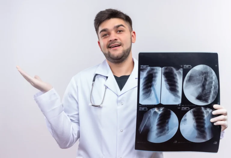 Young handsome doctor wearing white medical gown white medical gloves stethoscope glad with results tomography standing white wall